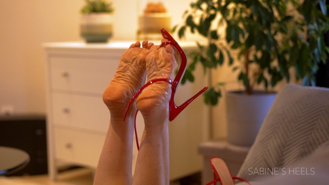RED SANDALS AND WRINKLED FEET DANGLING ON SOFA